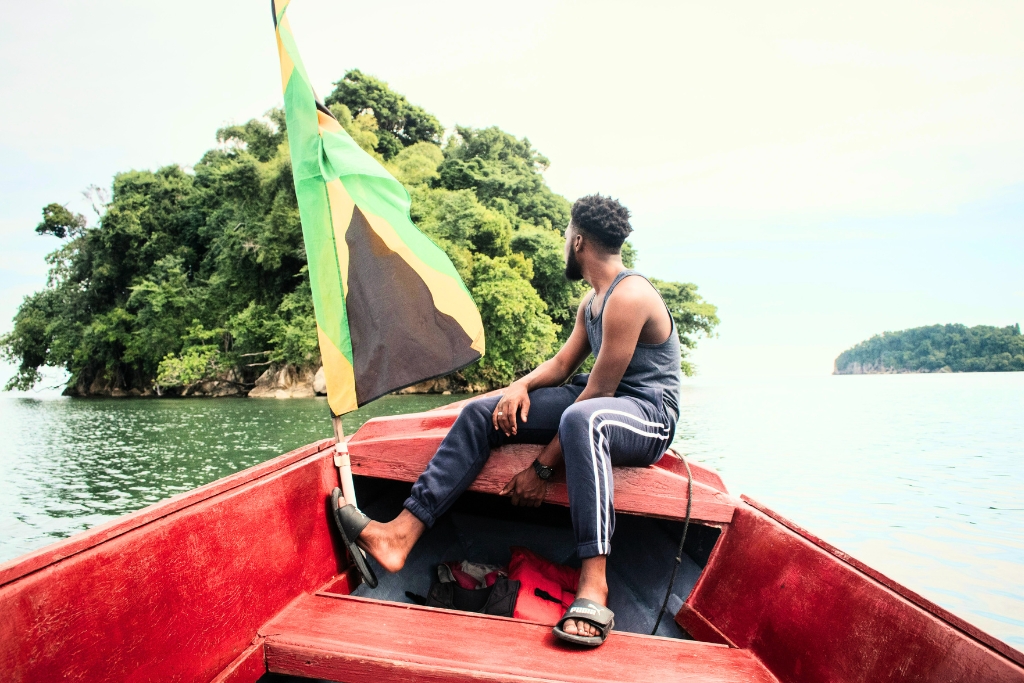 Jamican in a red boat sailing to another island 